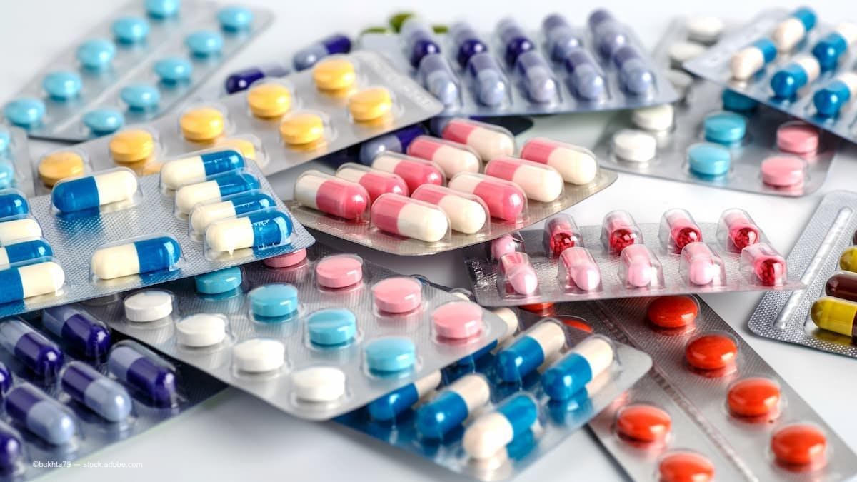 A collection of pills in plastic containers sitting on top of one another on a table. (Image Credit: AdobeStock/bukhta79)