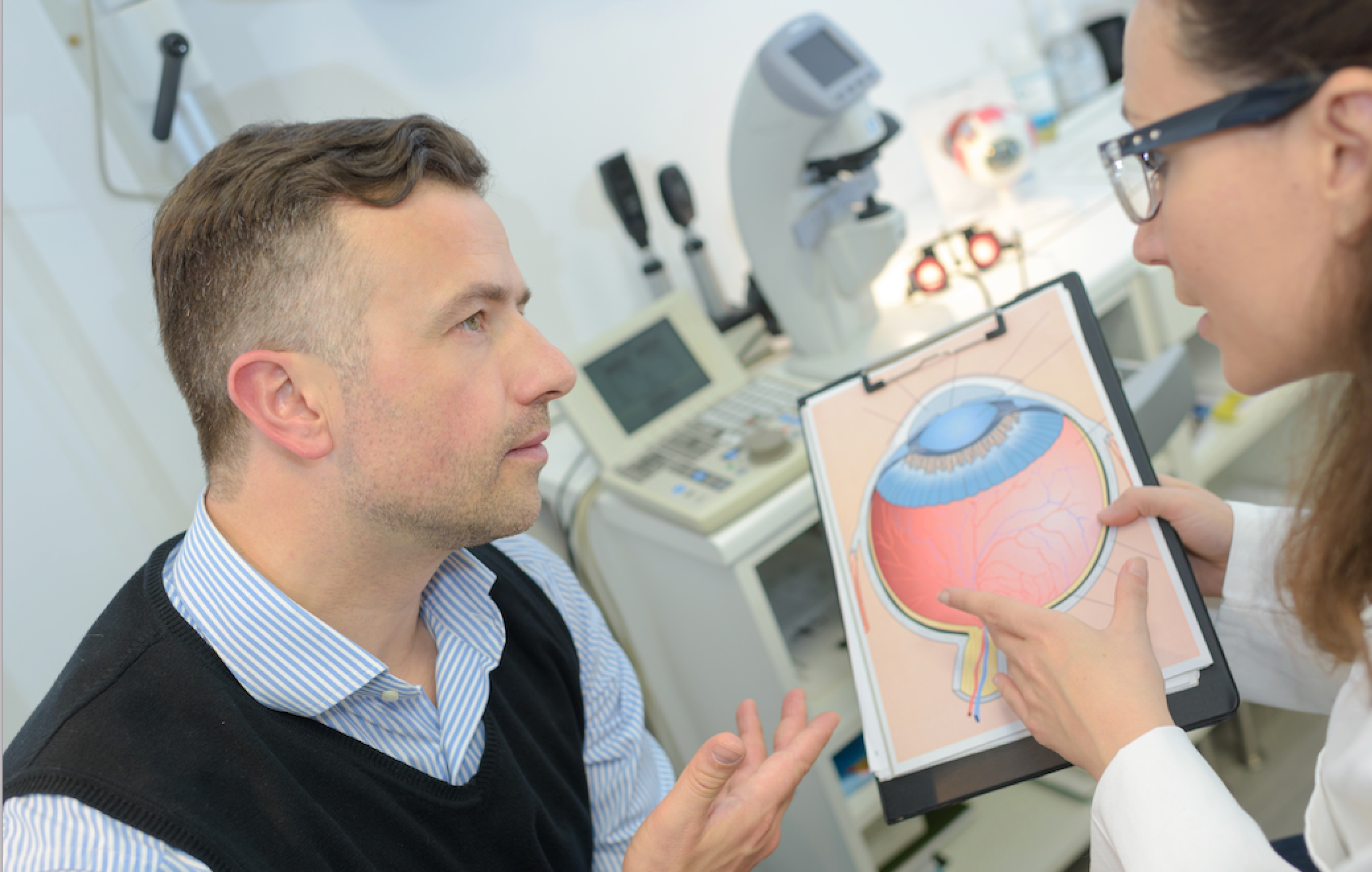 A doctor talking to a patient while pointing to a diagram of the eye