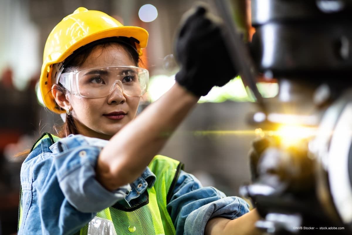 A woman working with heavy machinery while wearing protective eye glasses.