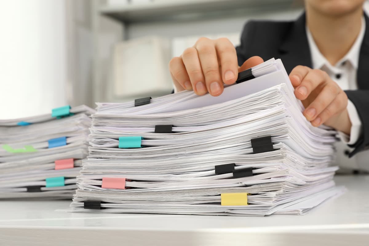 a business man going through a stack of papers. (Image Credit: AdobeStock)