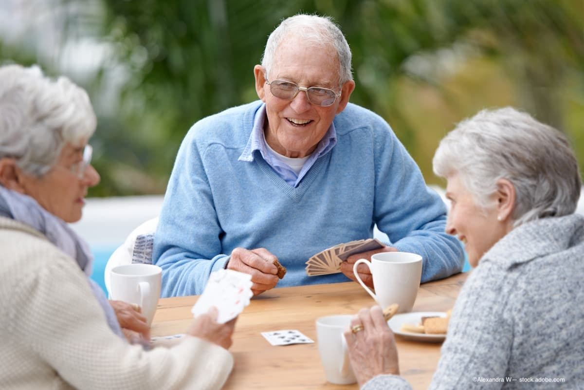 A group of senior citizens playing cards at a table. (Image Credit: AdobeStock/Alexandra W/peopleimages.com)