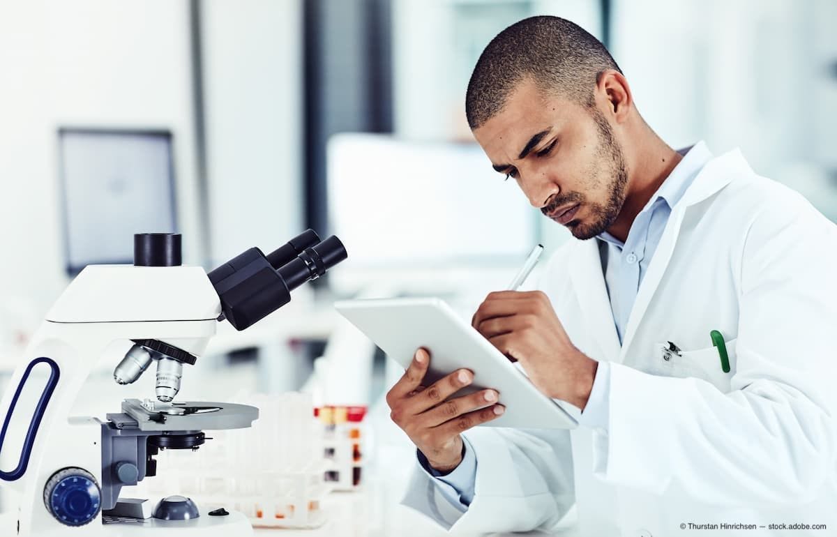 Serious male scientist working on a tablet reviewing an online phd publication in a lab (Image Credit: AdobeStock/Thurstan Hinrichsen)