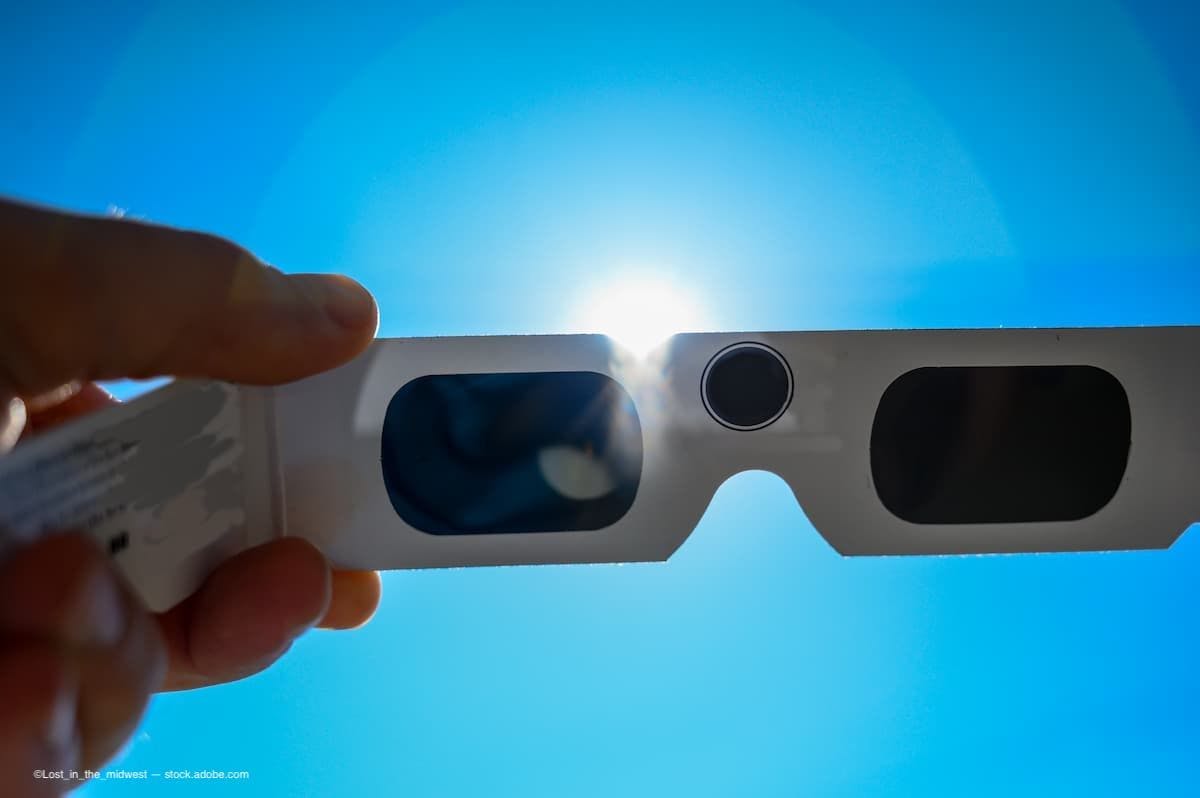 looking at a solar eclipse through protective glasses. (Image Credit: AdobeStock/Lost_in_the_midwest)