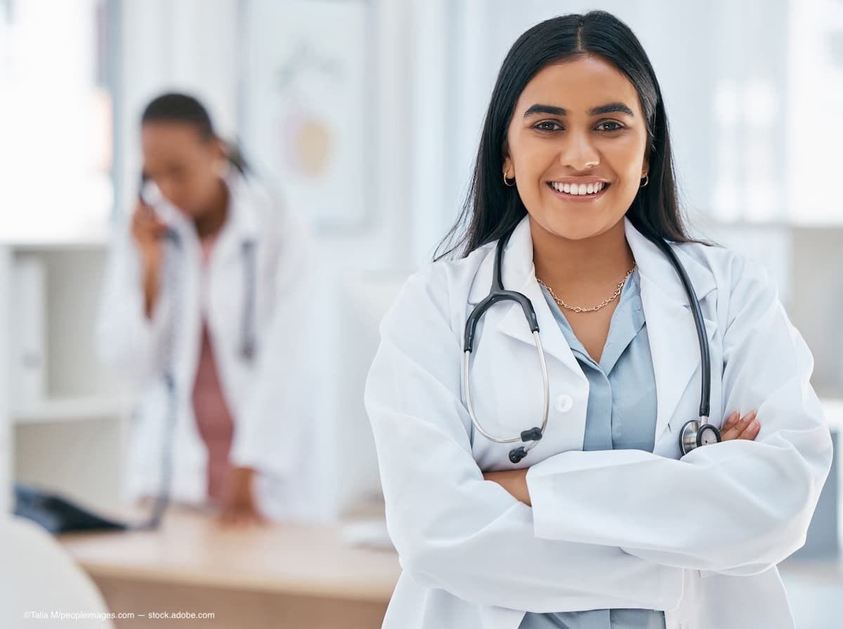 A woman doctor standing and smiling. (Image Credit: AdobeStock/Talia M/peopleimages.com)