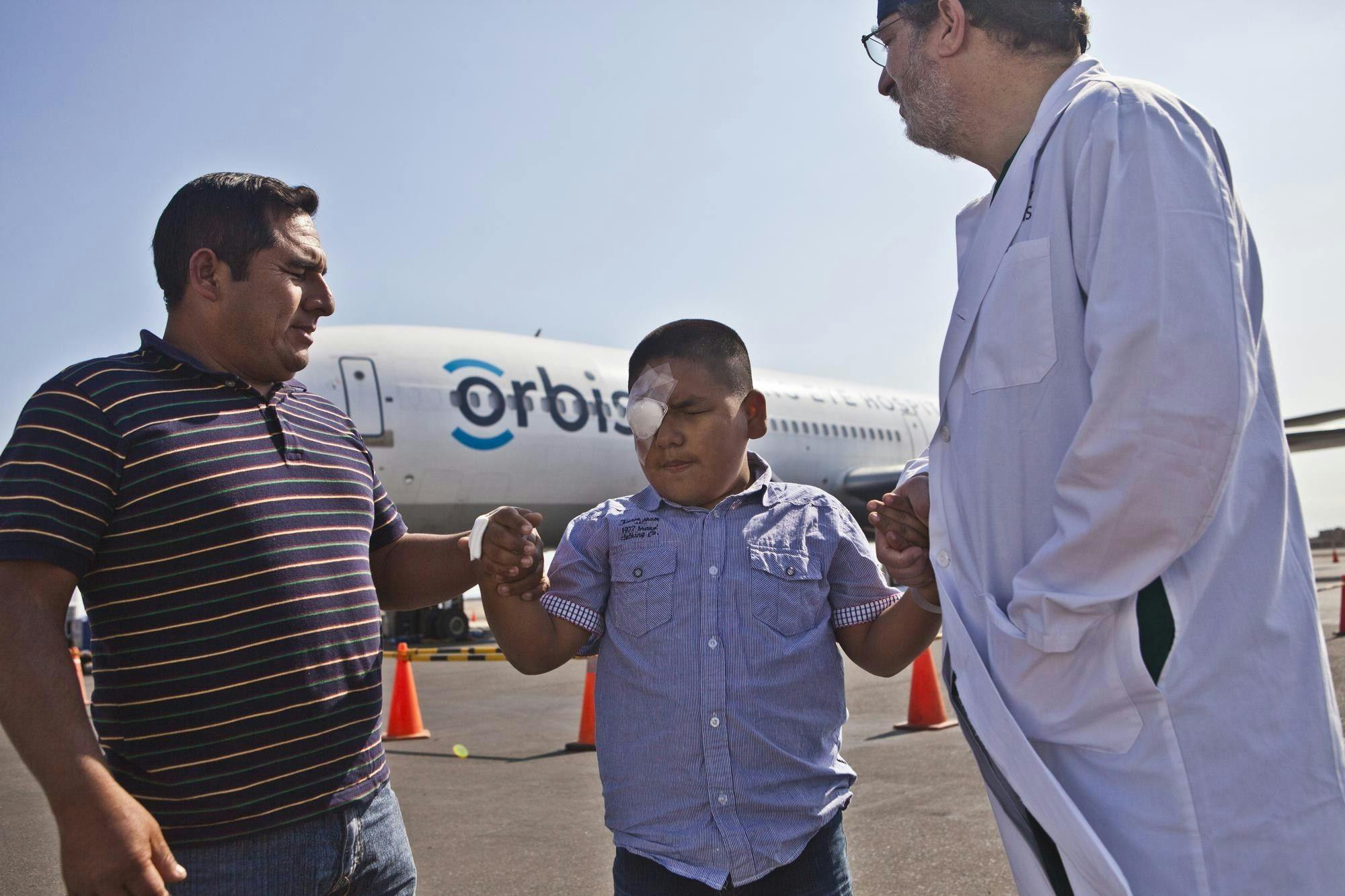 An Orbis Volunteer Faculty member, James Brandt, MD, of UC Davis, accompanies Giancarlo, 10, who received surgery for glaucoma during a Flying Eye Hospital project in Peru in 2014. During a training project commencing today, Orbis’s clinical staff and volunteer medical professionals along with UC Davis Health experts will share their knowledge with nearly 50 eye care professionals from Latin America, helping them fight avoidable blindness in their communities. (Image courtesy of Geoff Oliver Bugbee/Orbis)