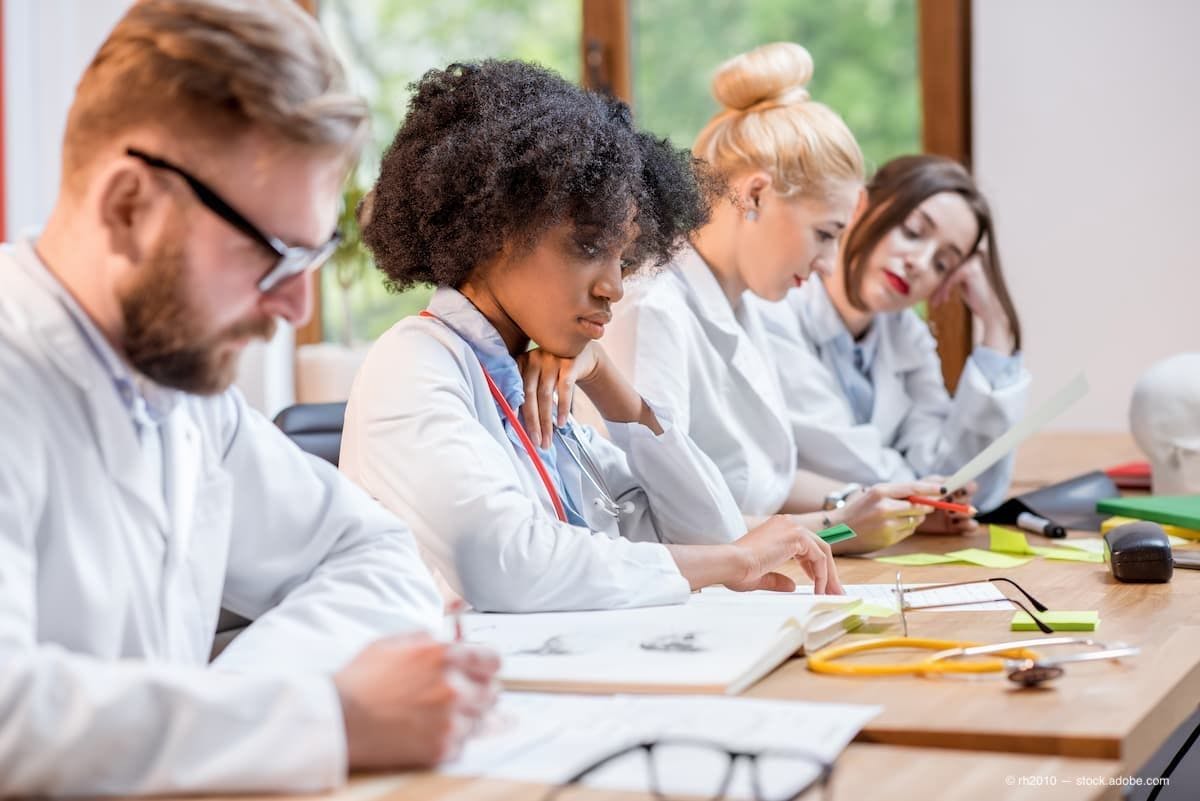 A group of medical students sitting at a classroom table (Image Credit: AdobeStock/rh2010)