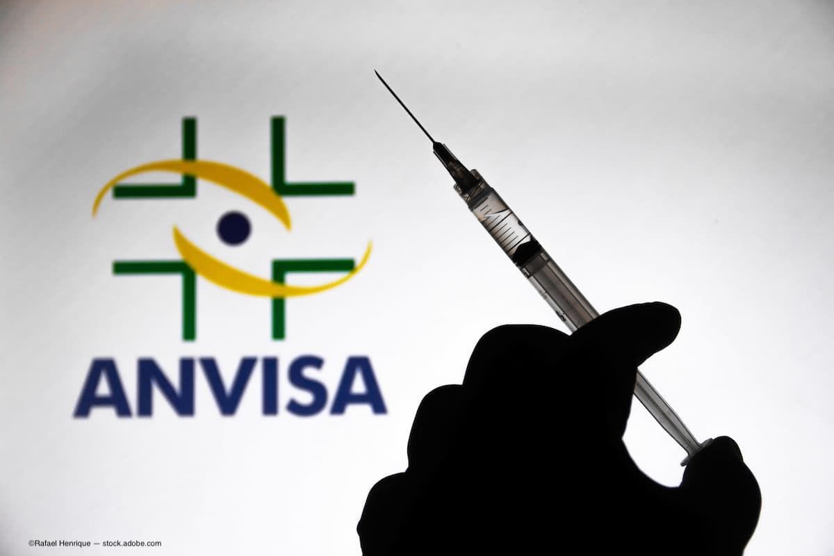 A person holding a syringe with the ANVISA logo in the background. (Image Credit: AdobeStock/Rafael Henrique)