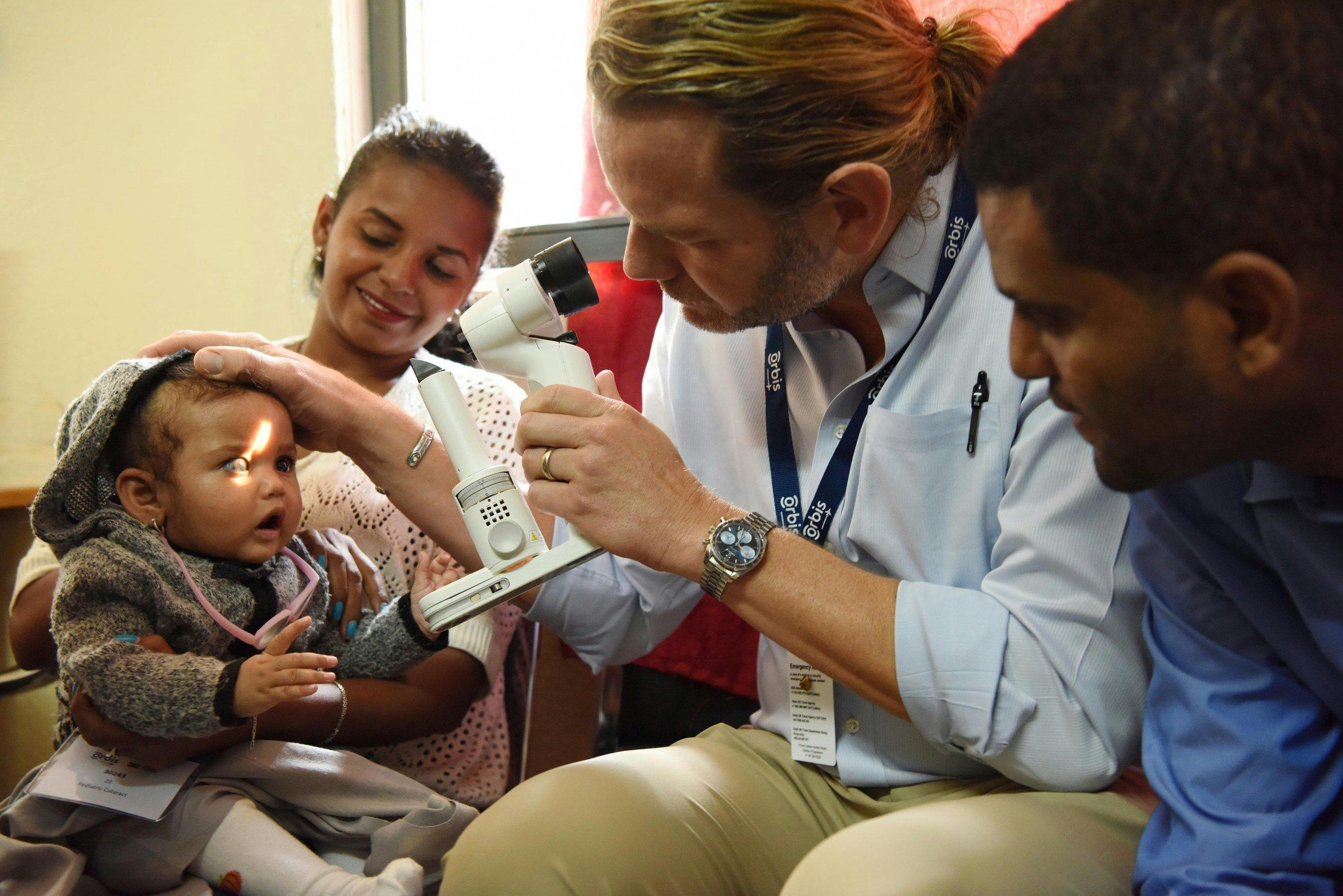 Nine-month-old Mary, who was born with glaucoma, is examined by Orbis Volunteer Faculty surgeon Daniel Neely, MD, during a Flying Eye Hospital program in Ethiopia in 2018. The virtual Flying Eye Hospital program will help eye care professionals in the country build their skills to treat glaucoma and cataract, leading causes of blindness and visual impairment, through online training. (Image courtesy of Geoff Oliver Bugbee/Orbis)