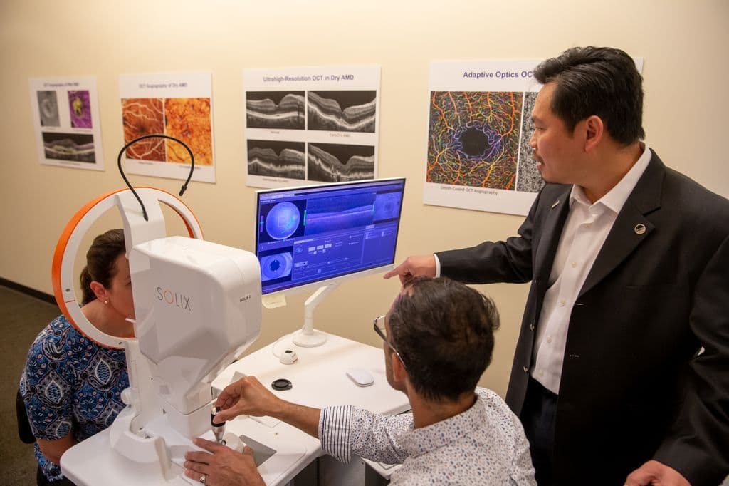 David Huang, MD, PhD, right, demonstrates a structural eye scan with the biomedical imaging technology he co-invented, optical coherence tomography, or OCT, at Oregon Health & Science University in Portland, Oregon. (Image courtesy of OHSU)