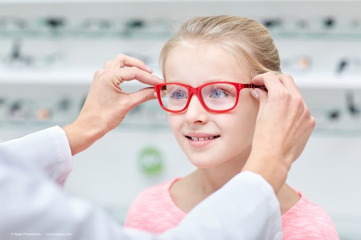 An optician putting glasses onto a young girl.  (Image Credit: AdobeStock/Syda Productions)